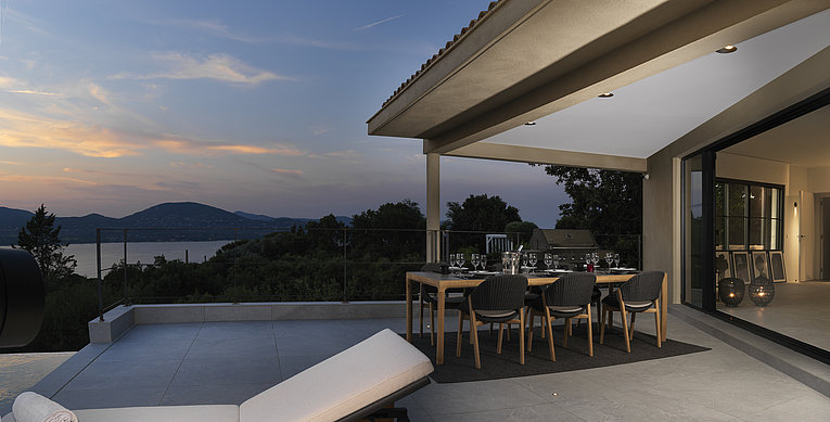 Althoff Villa Belrose in St. Tropez Côte d'Or Terrasse mit gedecktem Tisch und Stühle bei Nacht mit Meerblick im Sommer